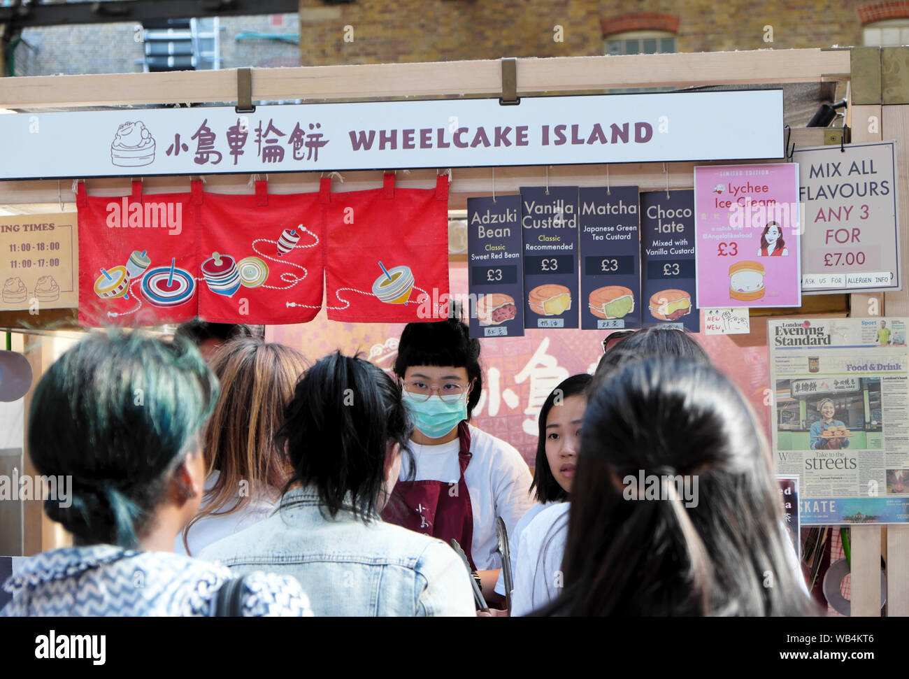Arbeitnehmer Tragen von Hygienemasken Servieren von Speisen an Wheelcake Insel Taiwan Shop & Kunden anstehen in Spitalfields Market London England UK KATHY DEWITT Stockfoto