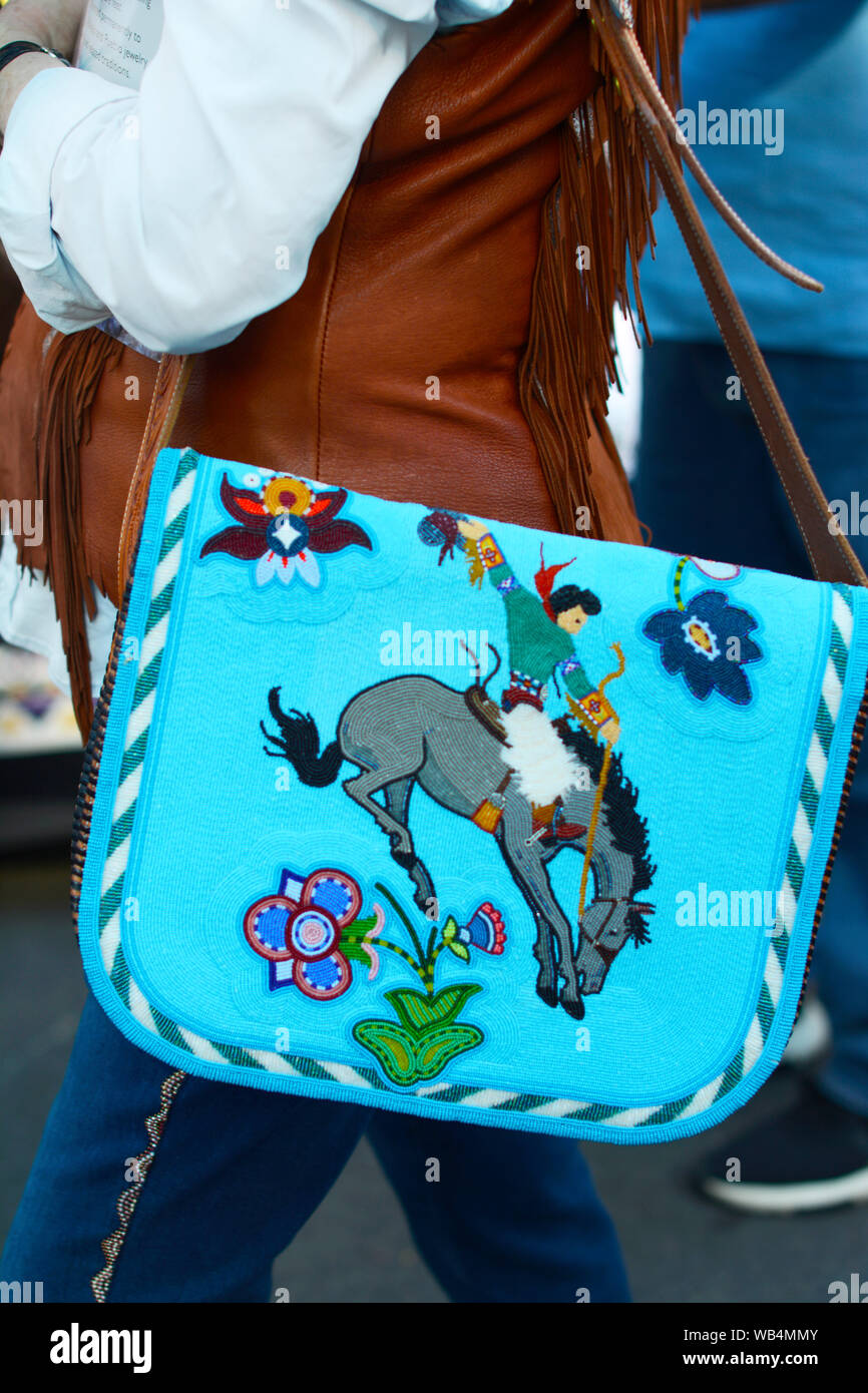 Eine junge Frau mit einer durchgehenden Native American Geldbeutel Besuche der Santa Fe indischen Markt in New Mexico, USA Stockfoto