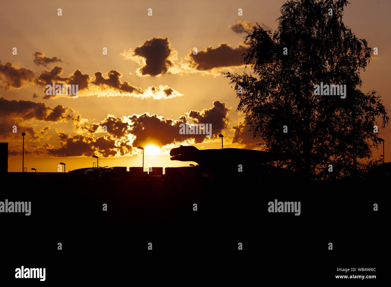 Sauropod Dino kommt in die Stadt. Eine Silhouette von Pflanzenfressern Dinosaurier in der Stadt mit einem dramatischen Himmel dahinter. Stockfoto
