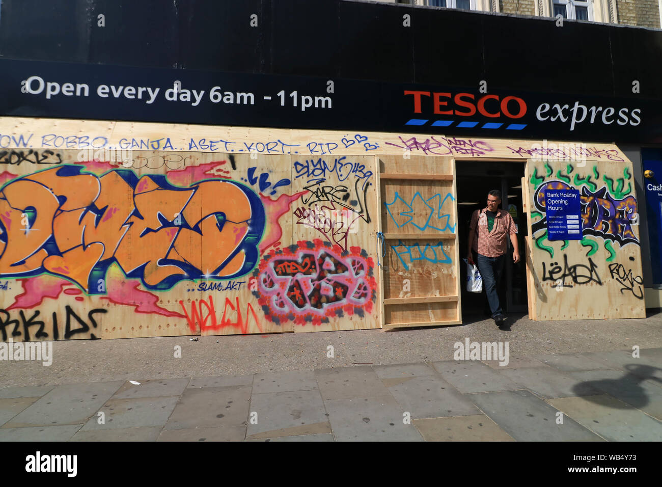 London, Großbritannien. 24 Aug, 2019. Ein Shopper, geht aus einem lokalen Supermarkt Tesco in Ladbroke Grove, für die Sicherheit vor der Notting Hill Carnival, Europas größte Street Festival feiert Westindische und karibischen Kultur mit Paraden in West London geentert, es voraussichtlich 1 Mio. Besuchern ein Wochenende zu gewinnen. Credit: Amer Ghazzal/SOPA Images/ZUMA Draht/Alamy leben Nachrichten Stockfoto