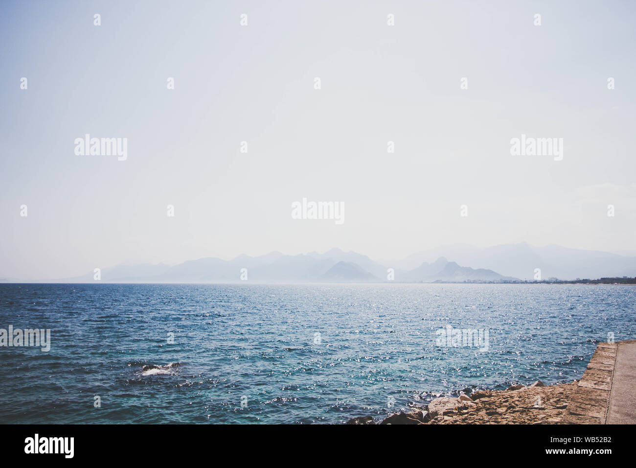 Die Wellen des Meeres Wasser waschen die Küste. In der Nähe der Küste eine Straße für wenige gebaut wurde. Auf der anderen Seite des Meeres, hohe Berge. Stockfoto