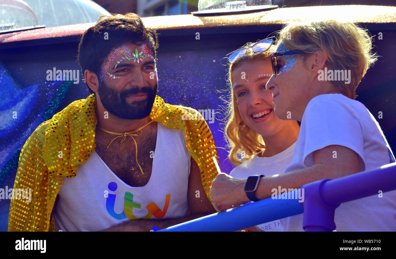 Coronation Street Sterne nehmen Teil an der Manchester, UK, LGBT Pride Parade am 24 August, 2019. Charlie De Melo (links) Wer spielt Imran Habeeb, trägt eine Gelbe Kap, wie er spricht, um zu Sally Dynevor (rechts), wer hat Sally Metcalfe in der Soap gespielt, seit 1986, als ihre 24-Jährige Tochter, Phoebe, steht zwischen ihnen. Stockfoto