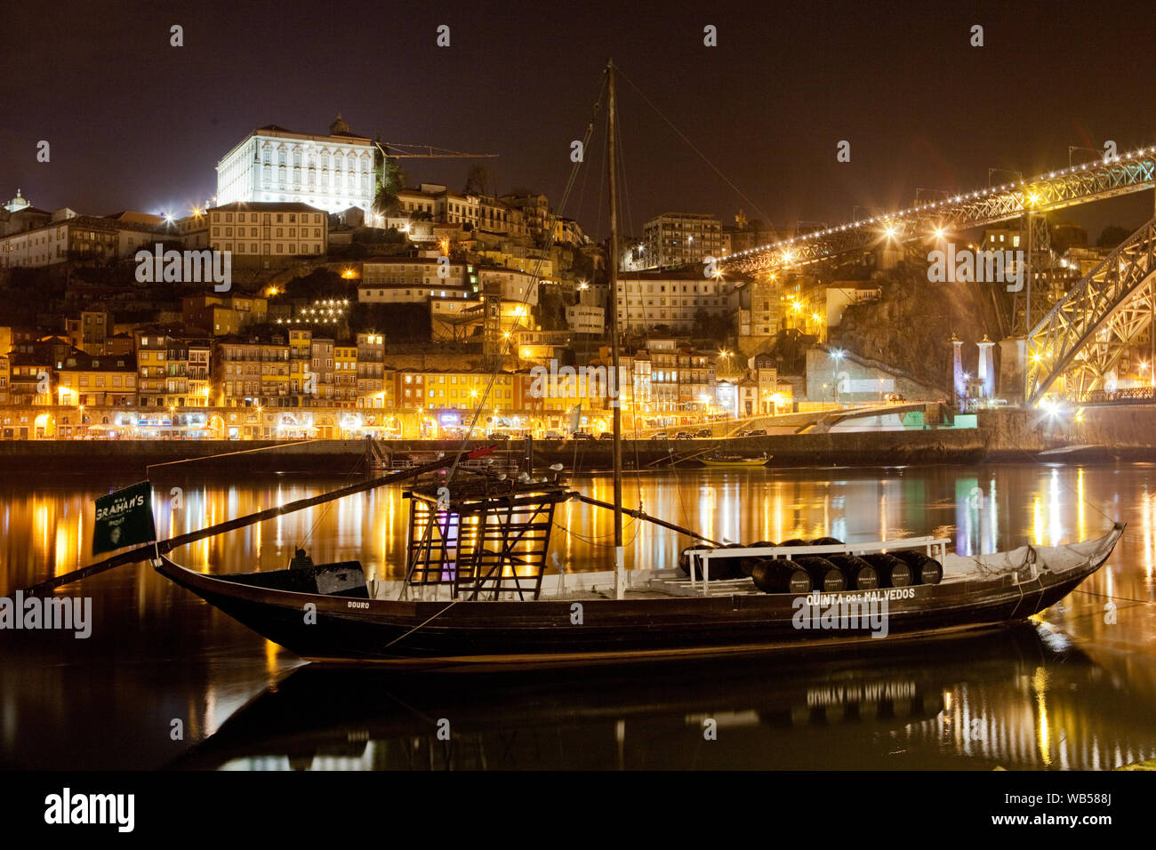 Lastkähne auf dem Fluss Douro (Rio Douro) mit der malerischen Stadt Porto bei Nacht beleuchtet in den Hintergrund und die Dom Luis Brücke - Portugal. Stockfoto