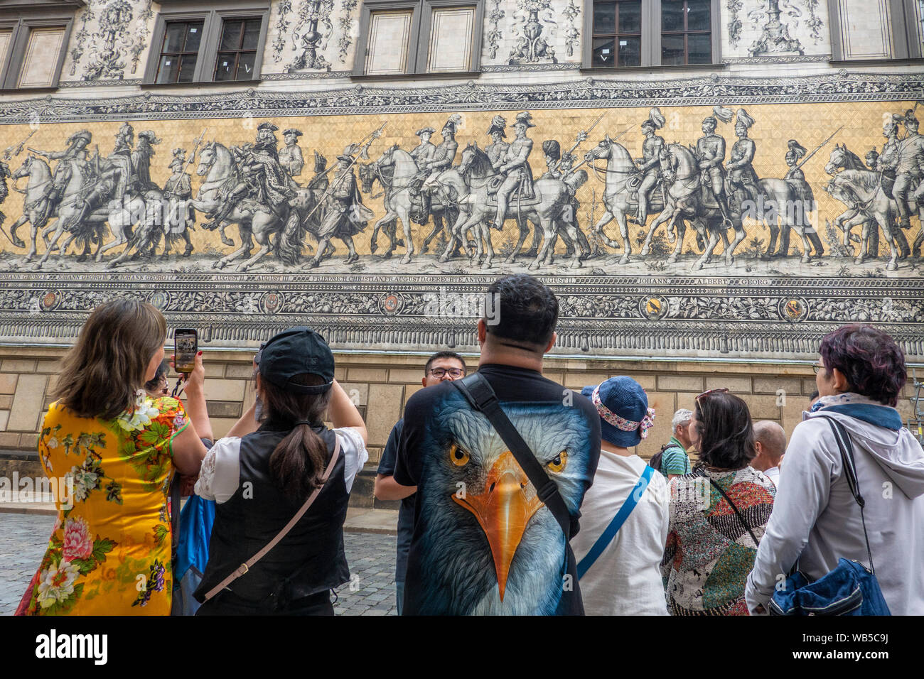 Dresden, Sachsen, Deutschland. Eine Gruppe von chinesischen Touristen bewundern die Wandgemälde der Fürstenzug (Fuerstenzug) aus Meissener Porzellan Stockfoto