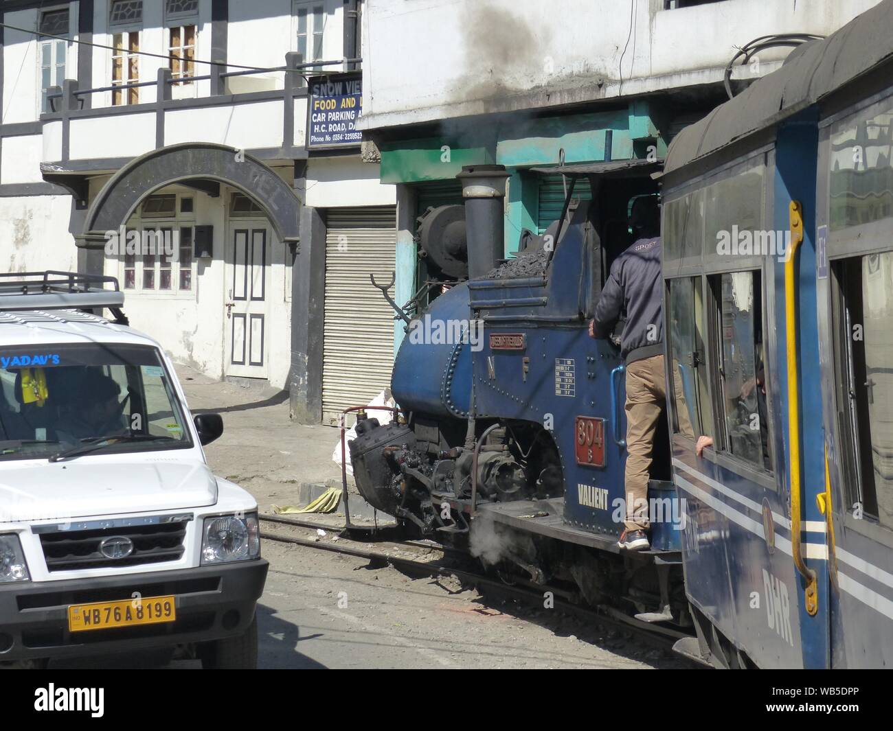 Ein Zug fährt ein Auto auf der Straße nähert sich Darjeeling. Stockfoto