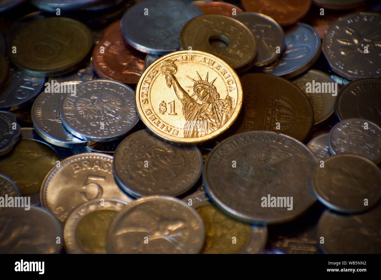American Gold Dollar scheint auf der Oberseite des Haufens von stumpfen Münzen aus anderen Nationen. Starke Wirtschaft inmitten Handelskriege. Stockfoto