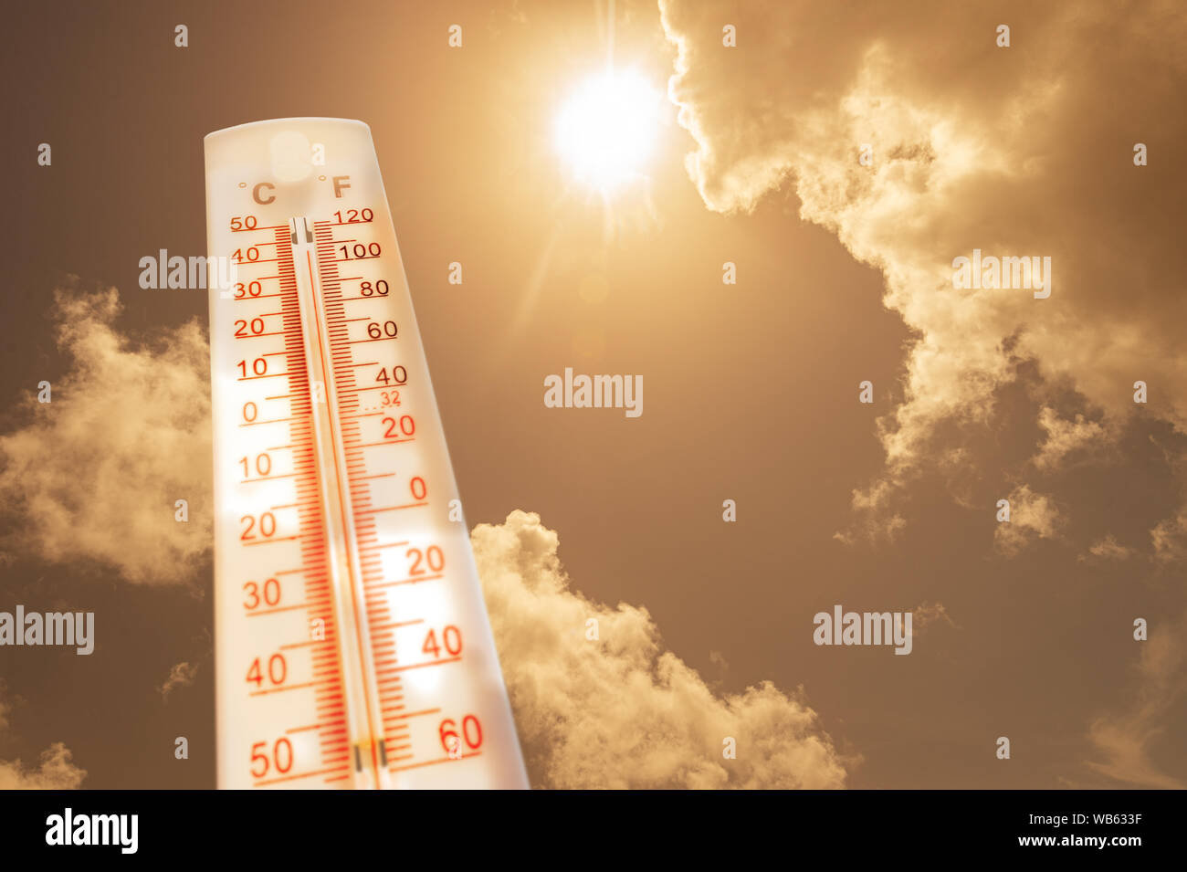 Thermometer vor Himmel mit Sonne und Wolken Stockfoto