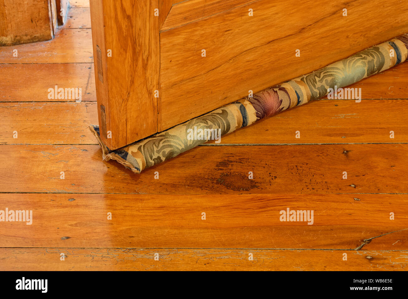 Eine nützliche Haus Erwärmung Werkzeug, einem Material, Entwurf Stopper unter einer hölzernen Tür auf einem Holzboden Stockfoto