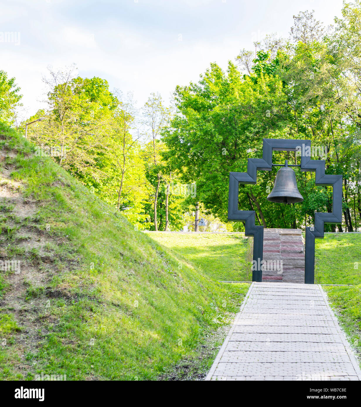 Christliche Kreuz mit einer Glocke innen auf grünem Gras Hintergrund an einem sonnigen Tag Stockfoto
