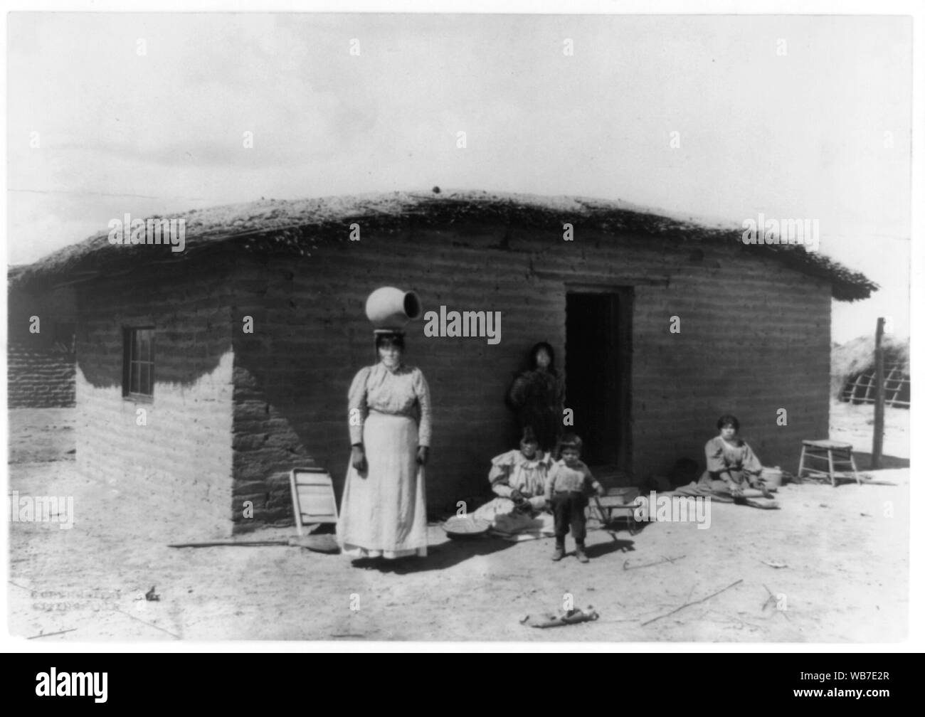 Fünf Pima Indianern Stellen außerhalb adobe Haus - eine Frau steht mit einem Stück der Töpferei auf dem Kopf Abstract / Medium: 1 Fotoabzug. Stockfoto