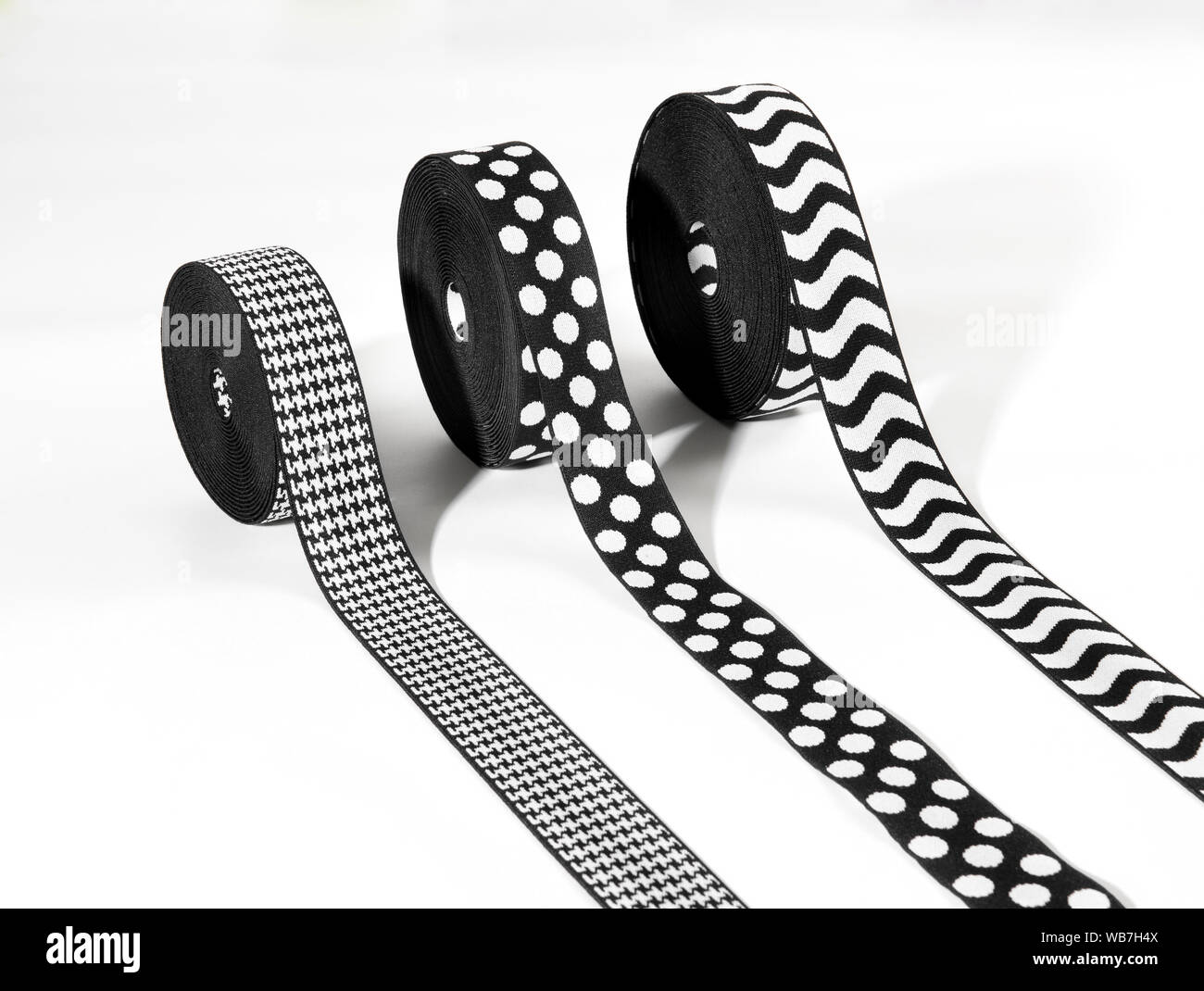 Drei Rollen von dekorativen schwarzen und weißen elastische Bänder oder Bänder mit Fischgrätmuster, Polka Dot und gewellten Streifen Muster angezeigt, auf einem weißen backgroun Stockfoto