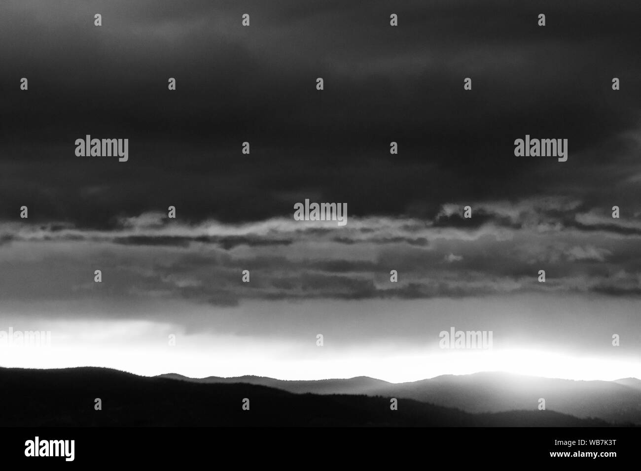 Blick auf die dunklen Wolken bei Sonnenuntergang, mit Sun Filterung durch ein Loch in den Berg Stockfoto