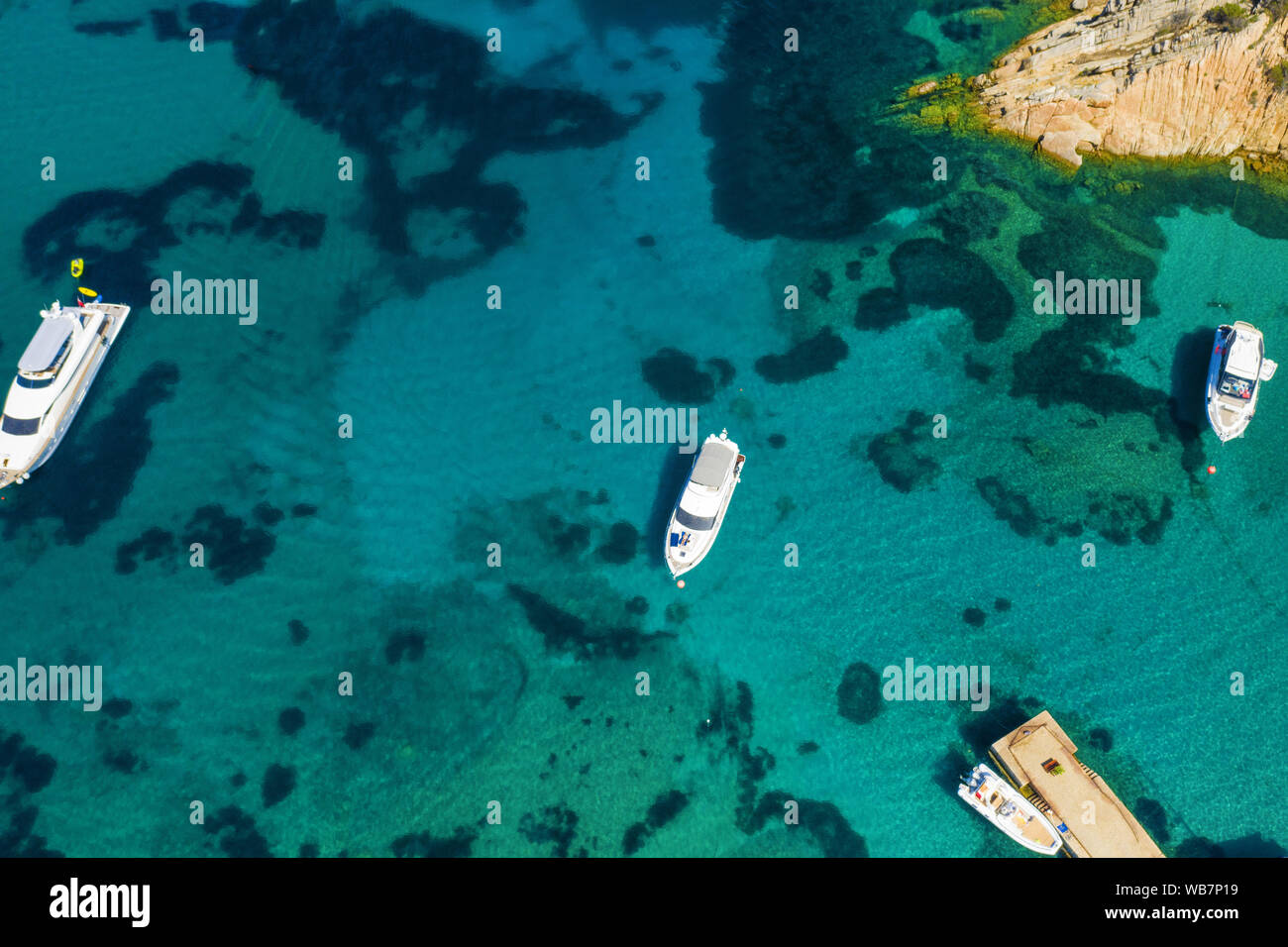 Ansicht von oben, beeindruckende Luftaufnahme von Luxus Yachten und Boote schwimmend auf einem smaragdgrünen Bucht von Wasser in Sardinien. Maddalena Archipel, Sardinien Stockfoto