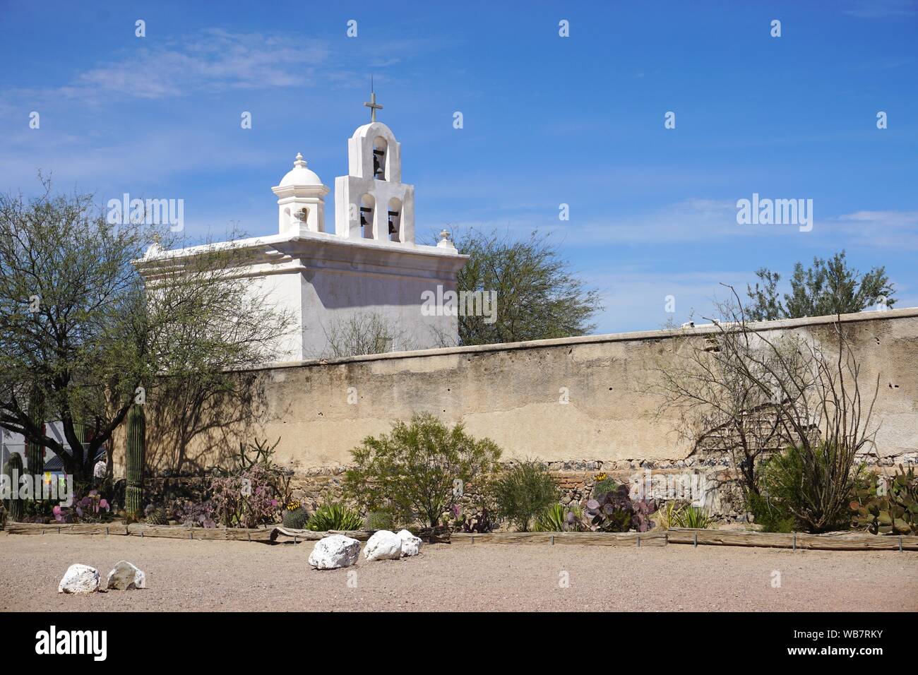 Die historische San Xavier Mission, in der Nähe von Tucson, Arizona, ist an einem sonnigen Frühlingstag über eine schmutzige adobe-wand unter einem hellblauen Himmel zu sehen Stockfoto