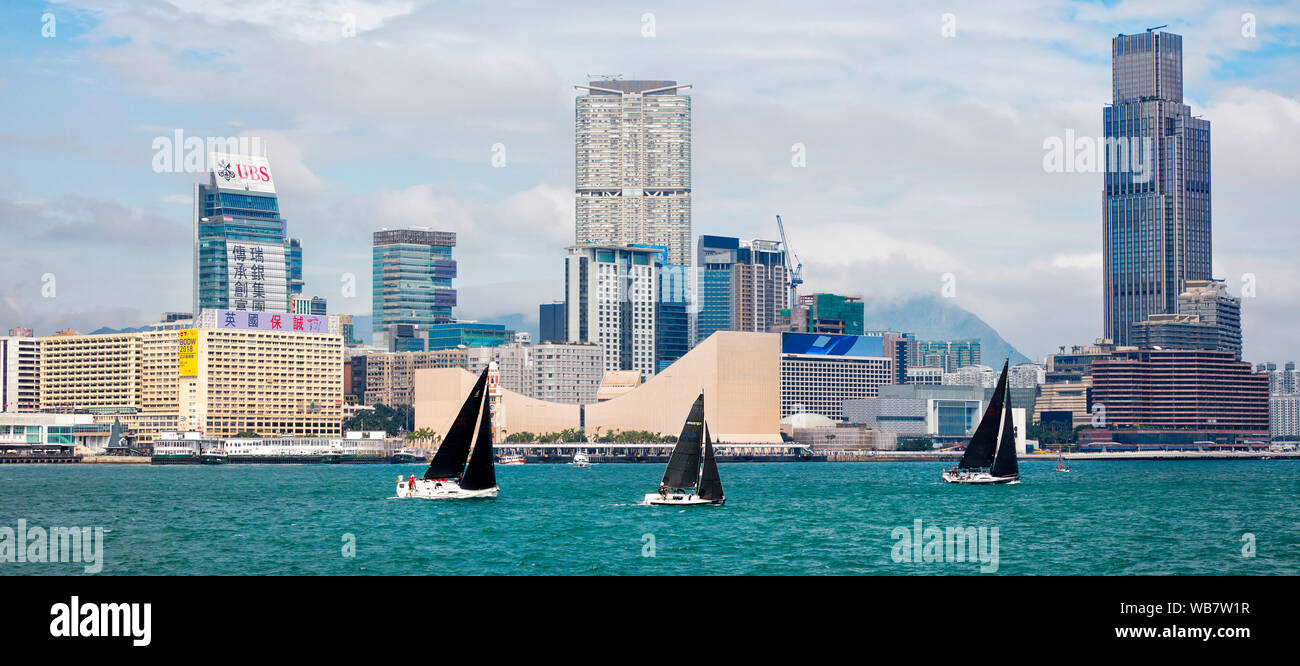 Boote segeln im Victoria Hafen mit Gebäuden auf der Kowloon Halbinsel im Hintergrund. Hongkong, China. Stockfoto