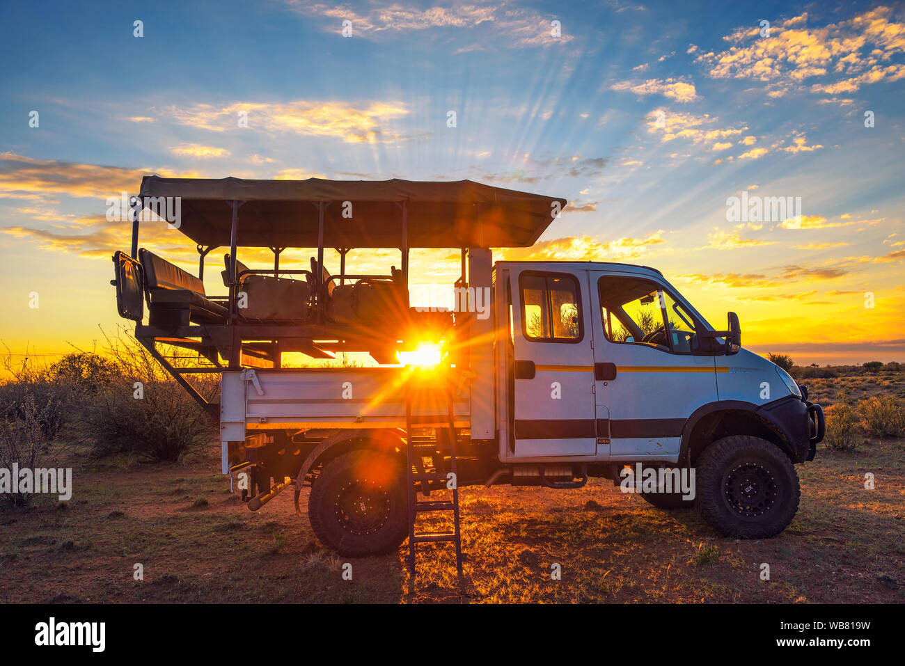 African Safari Fahrzeug stoppt in der Kalahari Wüste für die dramatischen Sonnenuntergang Stockfoto