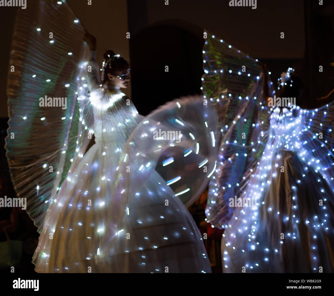 GRAGNOLA, LUNIGIANA, Italien - 10 AUGUST 2019: Stelzenläufer walker Damen tanzen in ihren beleuchteten Kostüme in lokalen Abend Festival. Stockfoto