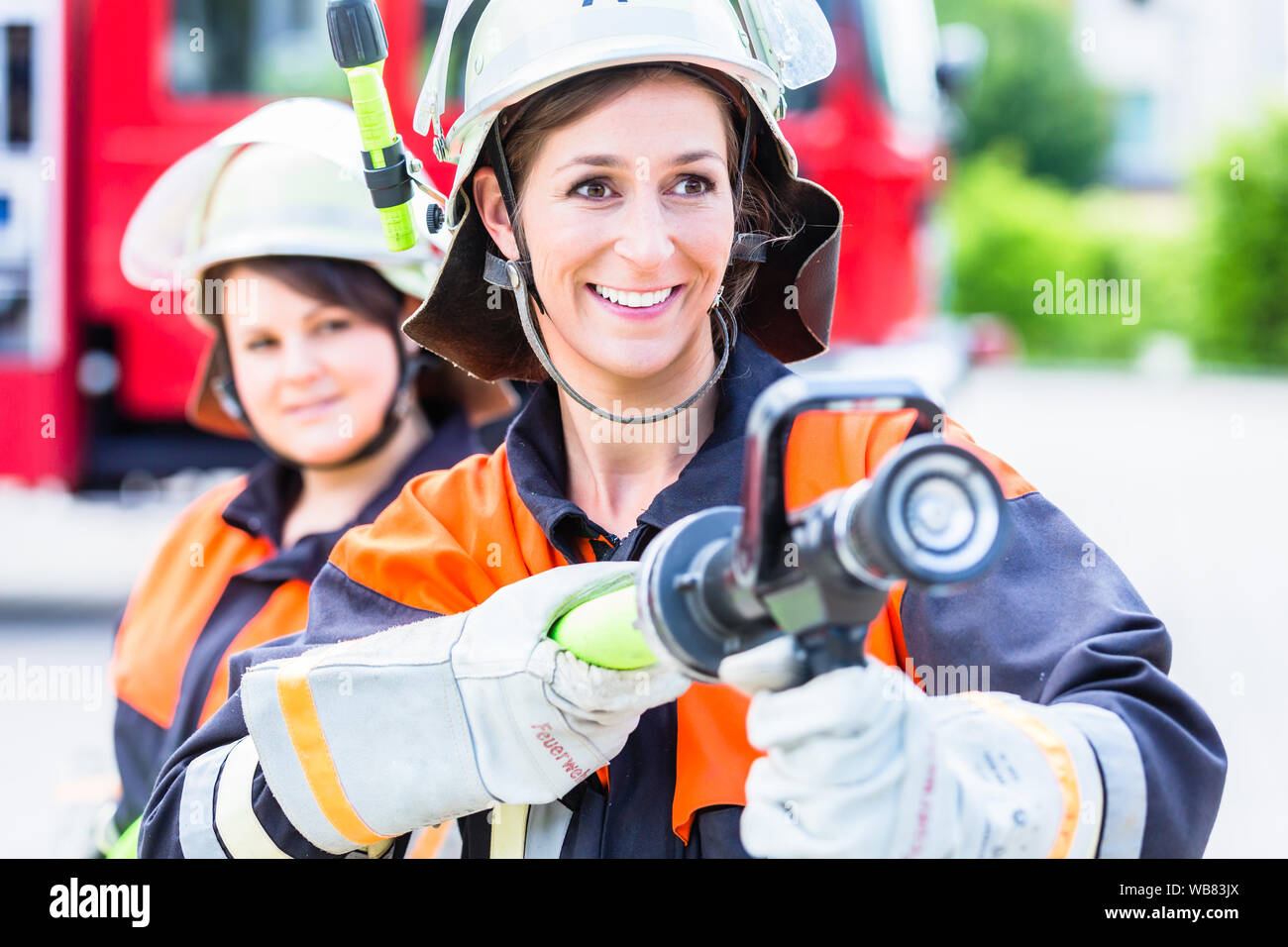 Weibliche Feuerwehrleute mit Wasser zu löschen. Stockfoto