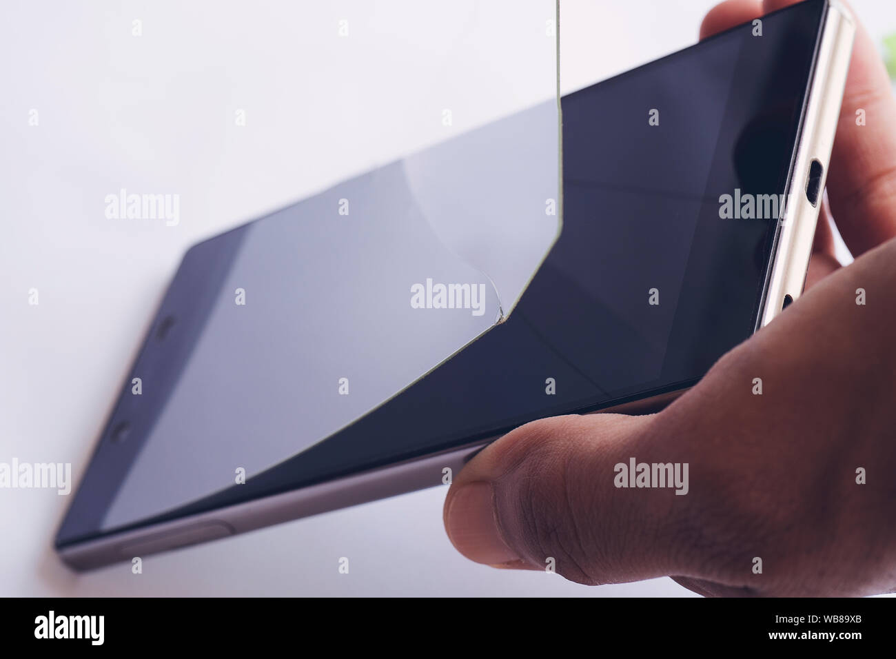 Hand entfernen beschädigt und Buntglasfenstern schützende Bildschirm des Smartphones film Stockfoto
