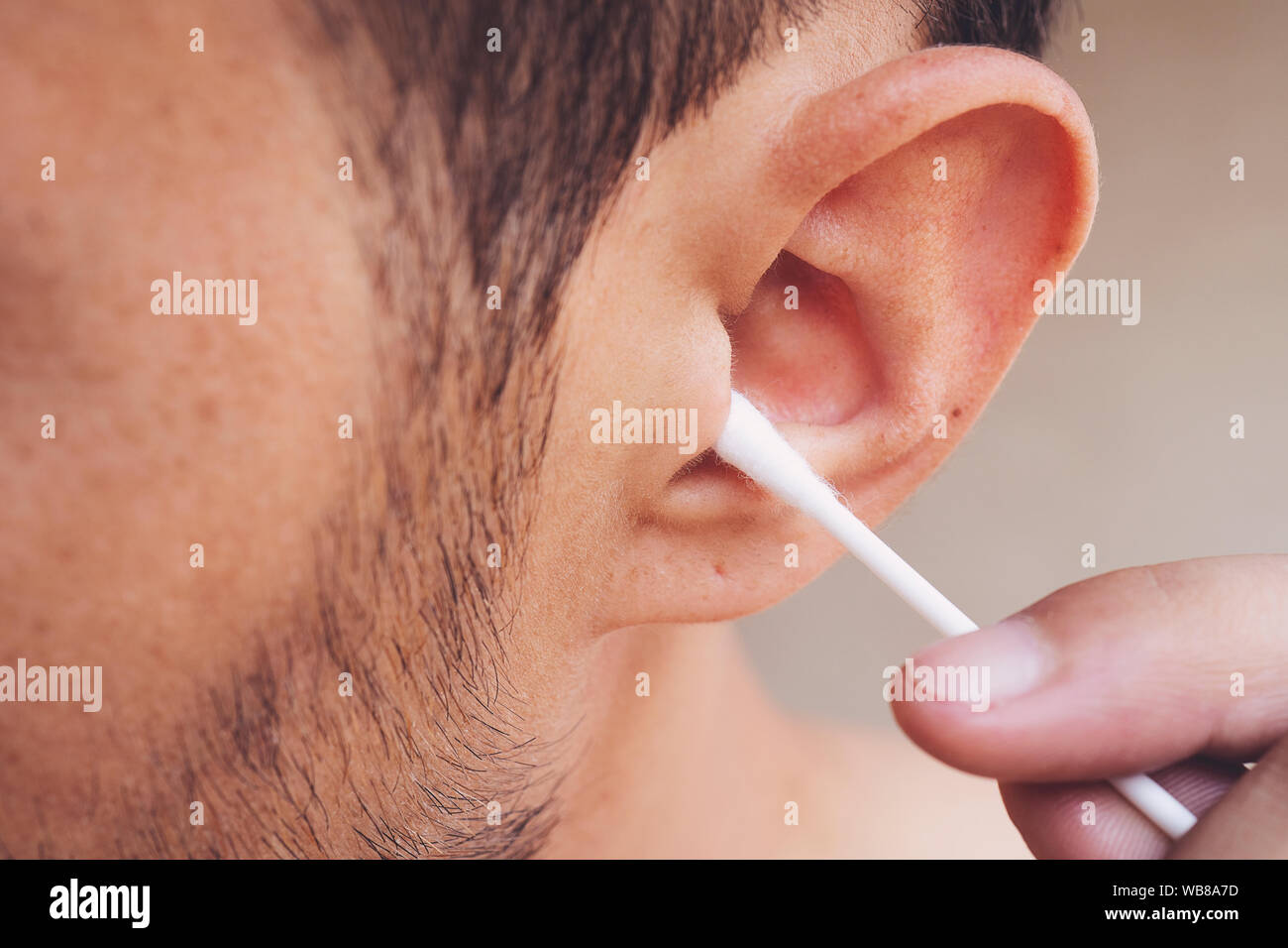 Mann über seine Ohren zu reinigen mit Q-Tip, Wattestäbchen. Hygiene  essentials Konzept. Entfernen von Wachs von Ohr Stockfotografie - Alamy