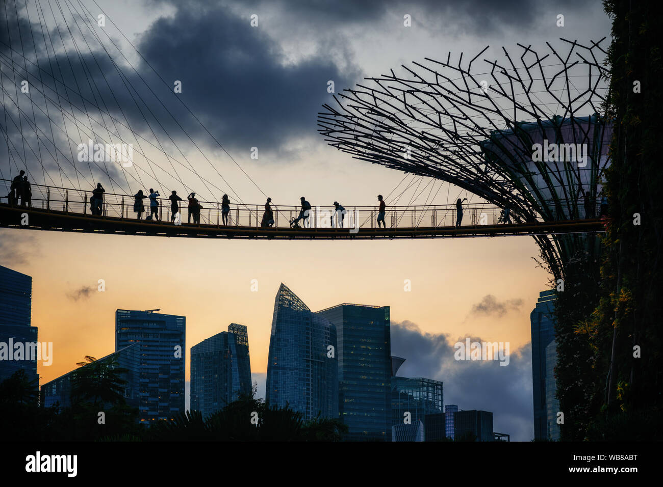 Sonnenuntergang von berühmten Wahrzeichen von Singapur mit Hängebrücke und touristische über Wolkenkratzer von Marina Bay Financial Center und futuristische Baum Stockfoto
