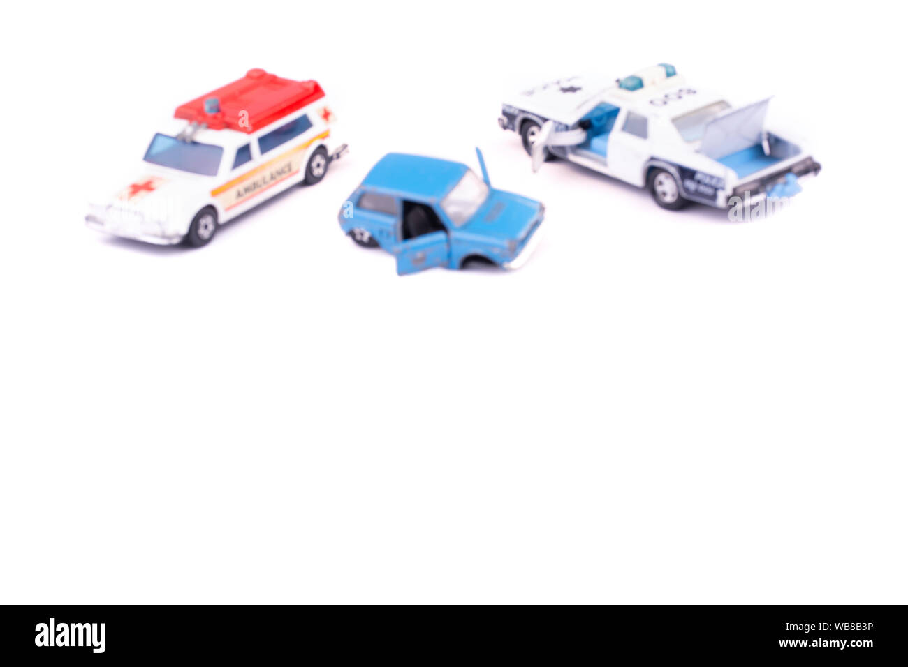 Verschwommenes Bild zertrümmert, und durch einen Unfall oder eine Störung kaputt Kinder Spielzeugauto auf weißem Hintergrund mit Krankenwagen und Polizei auf Crash isoliert sitzen Stockfoto