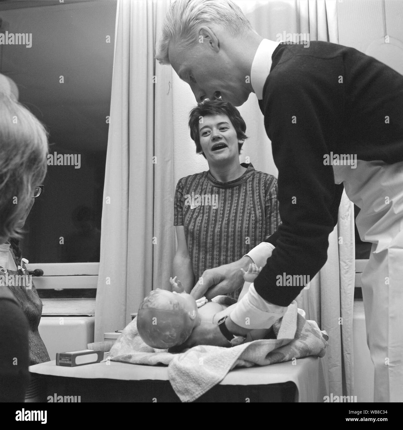 Lernen zu haben ein Baby in den 1960er Jahren. Eine Klasse, wie Sie kümmern sich um ein Baby. Eine Klasse, die Männer und Frauen, wenn Sie über die Eltern werden zum ersten Mal gehen. März 1963. Schweden Stockfoto