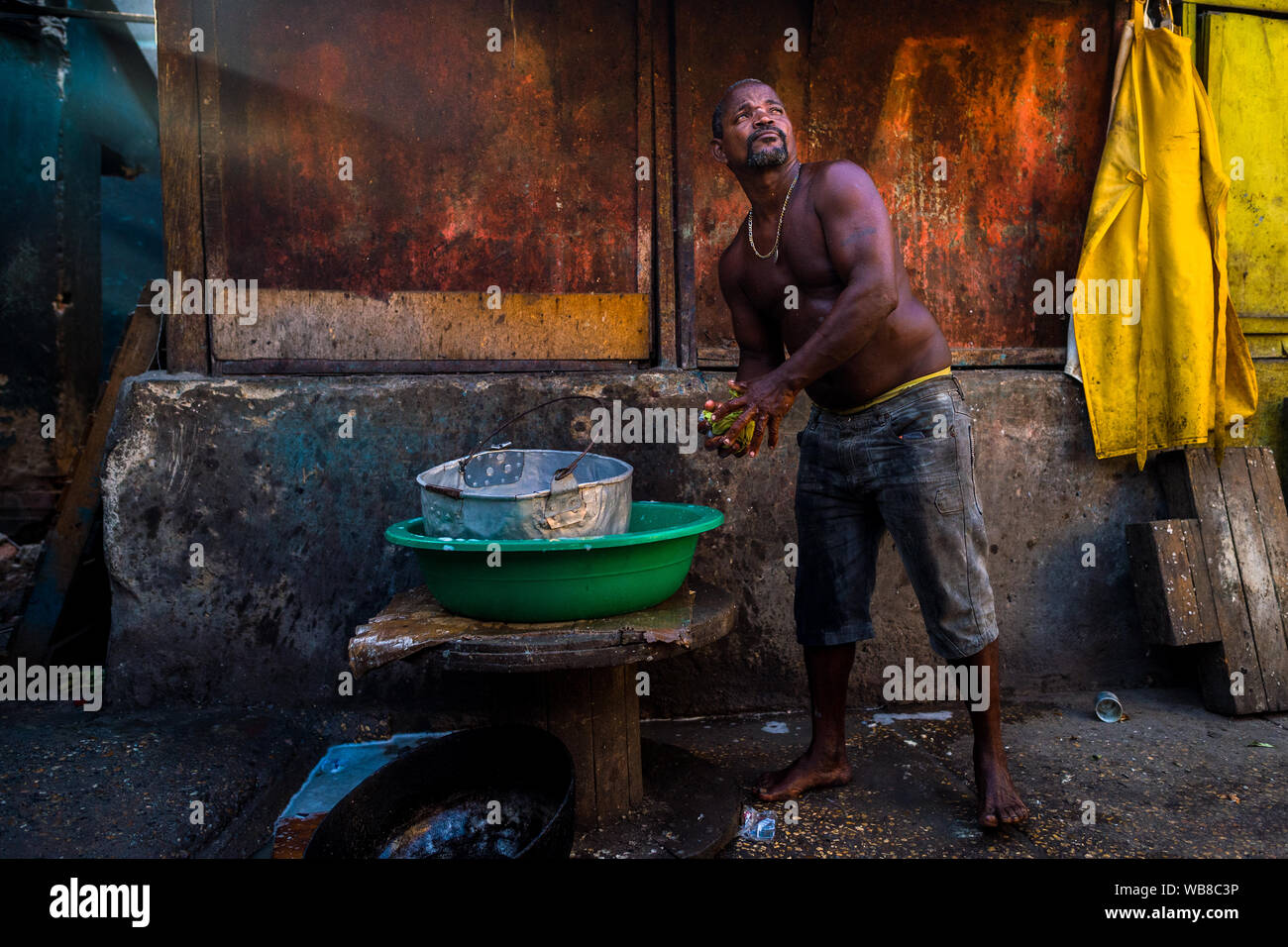 Ein Afro Mann wäscht Kochtöpfe am Ende der Schicht in einem Street Restaurant im Markt der Bazurto in Cartagena, Kolumbien. Stockfoto