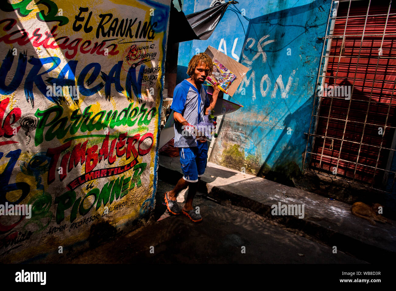 Ein Afro street Hersteller Spaziergänge rund um die Wand, mit Champeta Musik Propaganda bedeckt, auf dem Markt der Bazurto in Cartagena, Kolumbien. Stockfoto