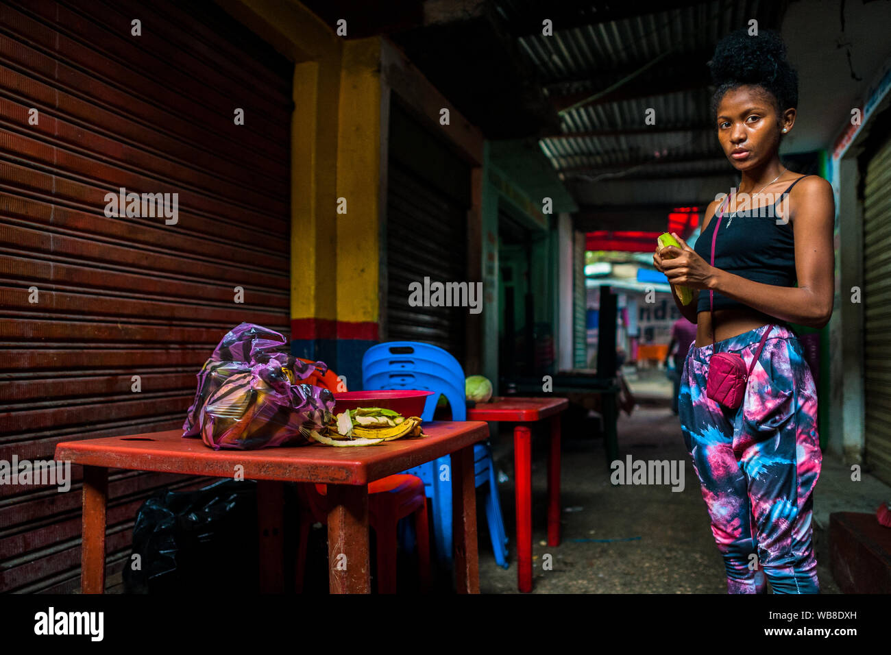 Ein Afro girl schält sie kochen Banane in einem Street Restaurant im Markt der Bazurto in Cartagena, Kolumbien. Stockfoto