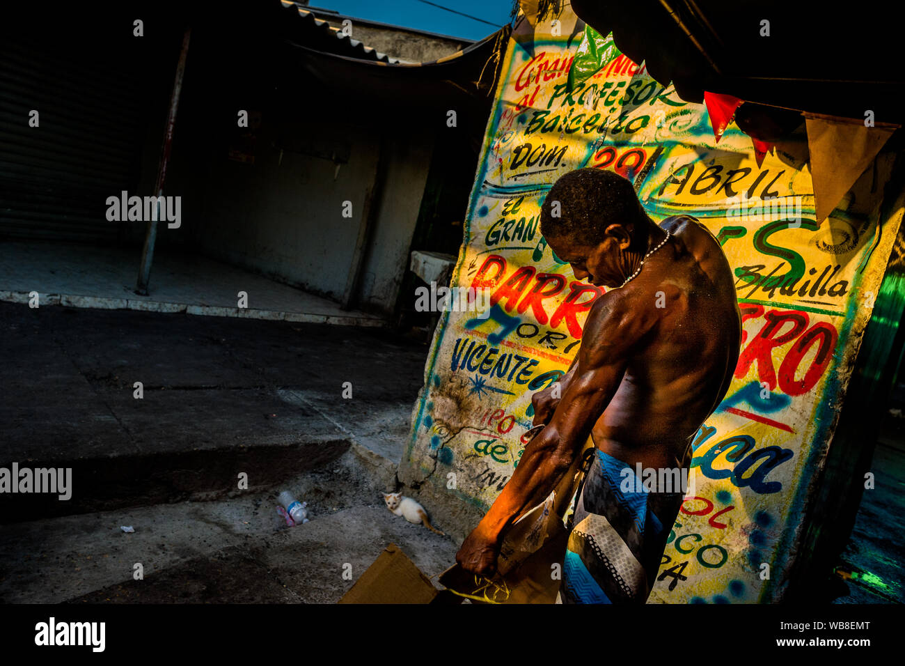 Eine afrokolumbianischen Obdachlosen Tränen aus Kartons vor der Wand, mit Propaganda bedeckt, auf dem Markt der Bazurto in Cartagena, Kolumbien. Stockfoto