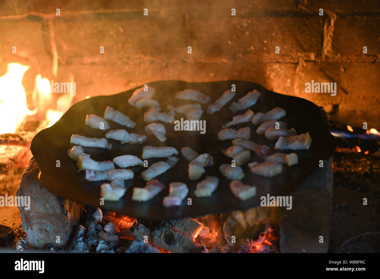 Salo ist in einer Pfanne in einem Ofen auf ein Feuer gebraten. Die Röstung Schmalz im Grill. Barbecue im Sommer im Freien. Schweinefett auf dem Scheiterhaufen. Kochen Street Food. r Stockfoto