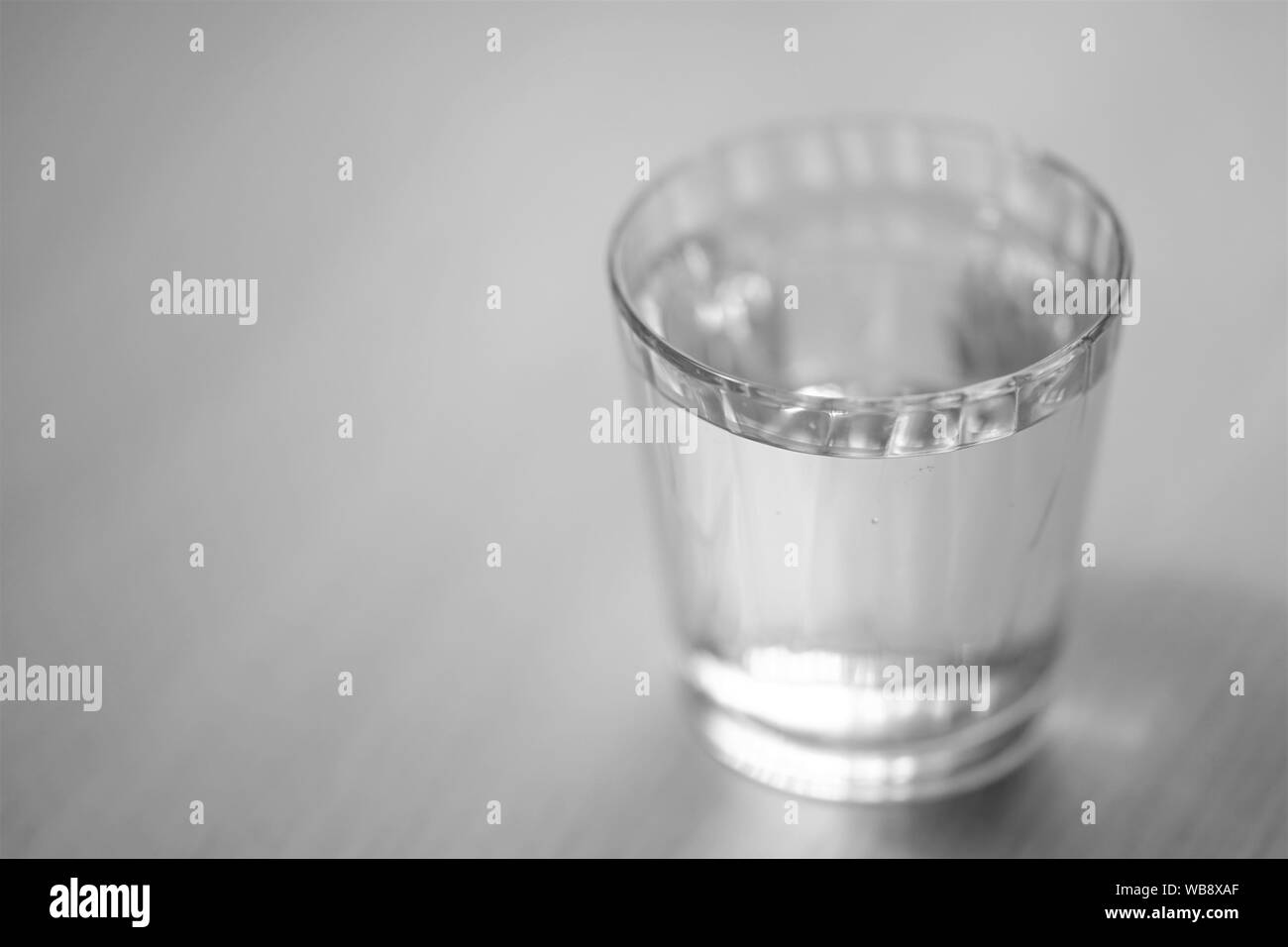 Glas voll Wasser auf dem Tisch, selektiver Fokus, Bw Stockfoto