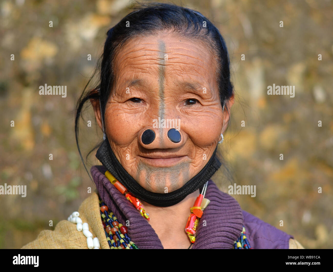 Alte Apatani tribal Frau mit schwarzem Holz- nase Stopfen (yaping hullo) und unverwechselbares Gesicht Tribal Tattoo posiert für die Kamera. Stockfoto