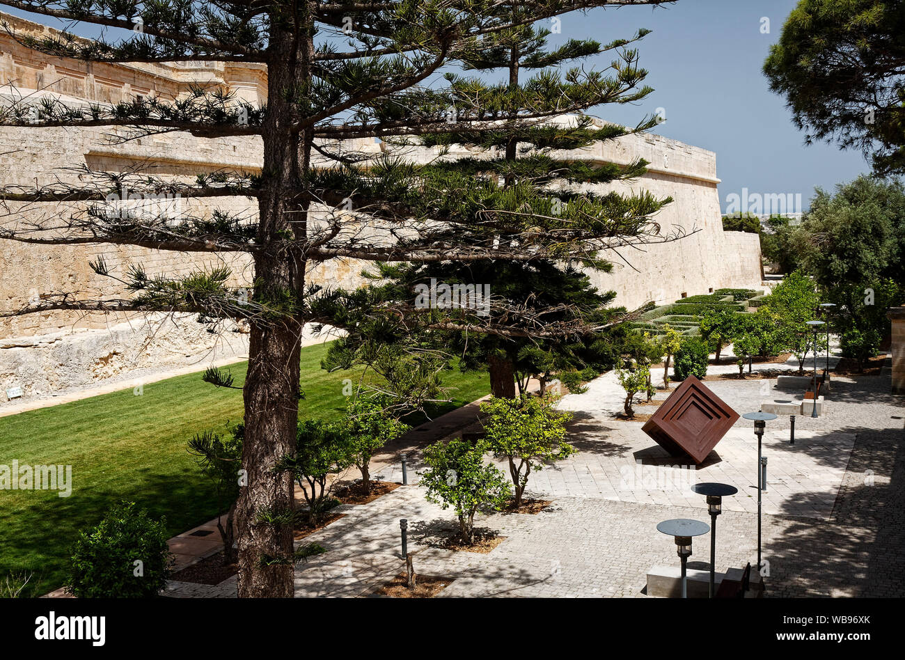 Alte Stadtmauer; befestigte Stadt; 16. bis 18. Jahrhundert; grasartige Wassergraben, moderne Skulptur, Straßenbeleuchtung, Bäume, Sträucher, Europa, Medina, Mdina, Malta, Frühling, horiz. Stockfoto