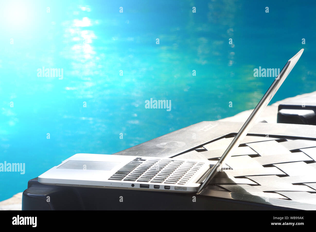 Laptop auf einem Liegestuhl in der Nähe des Swimmingpools. Von der Seite. Stockfoto