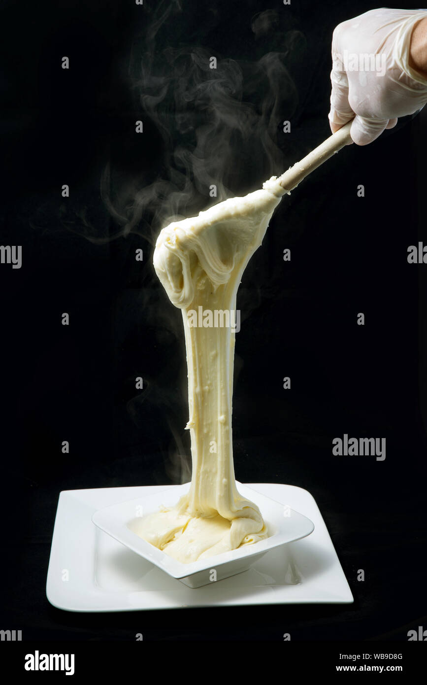 Eine warme künstlerische Held Schuß von frischem, heißem Käse serviert auf einem Tablett mit Rauch aus der gestreckten Käse auf einen minimalen weißen Hintergrund fr Stockfoto