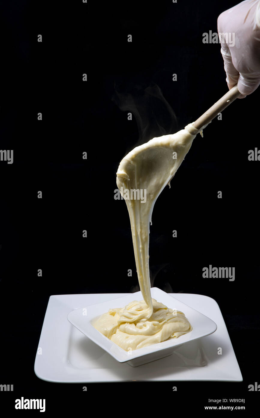Ein hoher Kontrast künstlerische Held Schuß von frischem, heißem Käse serviert auf einem Tablett mit Rauch aus der gestreckten Käse auf einen minimalen weißen Hintergrund Stockfoto
