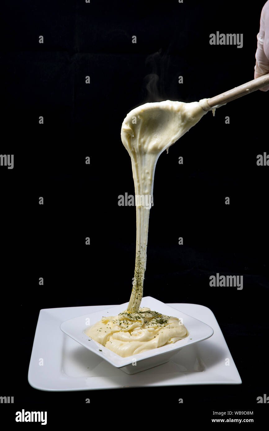 Ein hoher Kontrast künstlerische Held Schuß von frischem, heißem Käse serviert auf einem Tablett mit Oregano bestreut auf einer minimalen weißen Hintergrund von einem flachen h Stockfoto