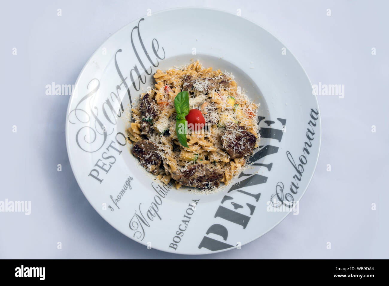 Ein hoher Kontrast hero Schuß eines Thunfisch Thunfisch pasta/Tapenade mit Oliven, Tomaten und Salat, auf einen minimalen weißen Hintergrund mit einem Winkel von 45 Grad von Zoom Stockfoto