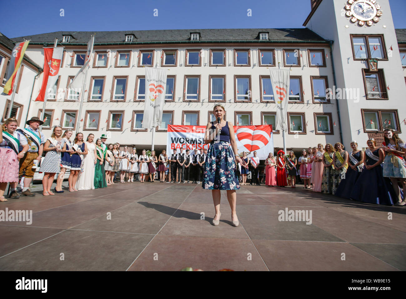 Worms, Deutschland. 24. August 2019. Die Rhine-Hessian Weinkönigin Anna Göhring Adressen die Eröffnungsfeier der Backfischfest 2019, von mehreren lokalen Wein Majestäten aus der Gegend um Würmer umgeben. Der größte Wein- und Volksfest am Rhein, das backfischfest in Worms begann mit der traditionellen Übergabe der Macht aus dem Oberbürgermeister, dem Bürgermeister von der Fischer, Lea. Die Zeremonie wurde von Tänzen und Musik umrahmt. Stockfoto
