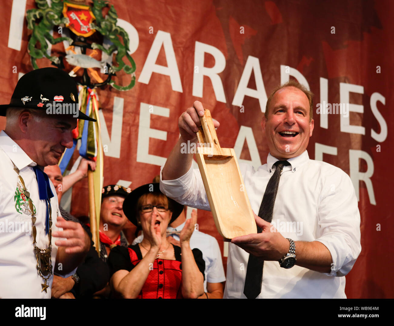 Worms, Deutschland. 24. August 2019. Randolf Stich, der Staatssekretär im Innenministerium von Rheinland-pfalz, hält die Leer traditionelle Handnirsch (Holz- Pfanne) bei der Eröffnung des Backfischfest 2019. Der größte Wein- und Volksfest am Rhein, das backfischfest in Worms begann mit der traditionellen Übergabe der Macht aus dem Oberbürgermeister, dem Bürgermeister von der Fischer, Lea. Die Zeremonie wurde von Tänzen und Musik umrahmt. Stockfoto