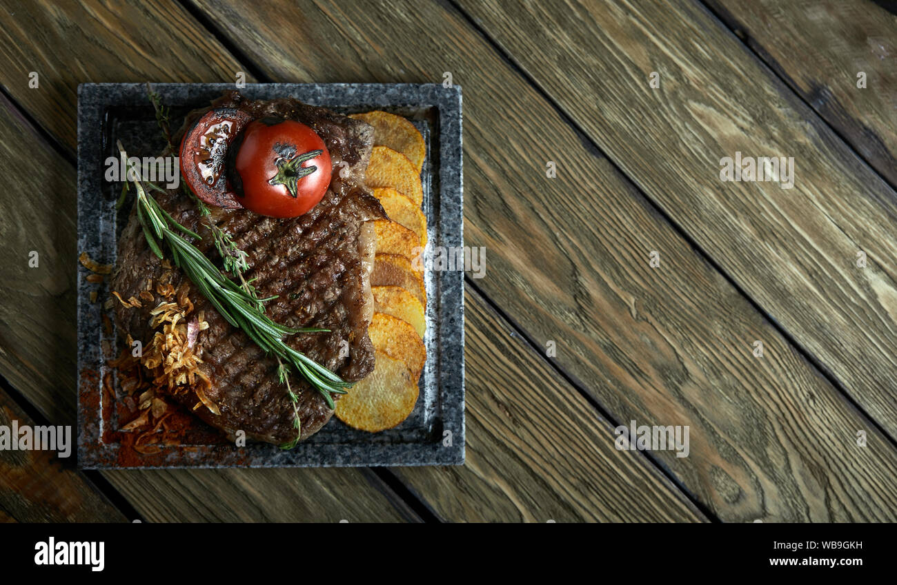 Gegrilltes Steak mit Messer und Gabel auf schwarzen Stein Schiefer geschnitzt. Steak auf dem