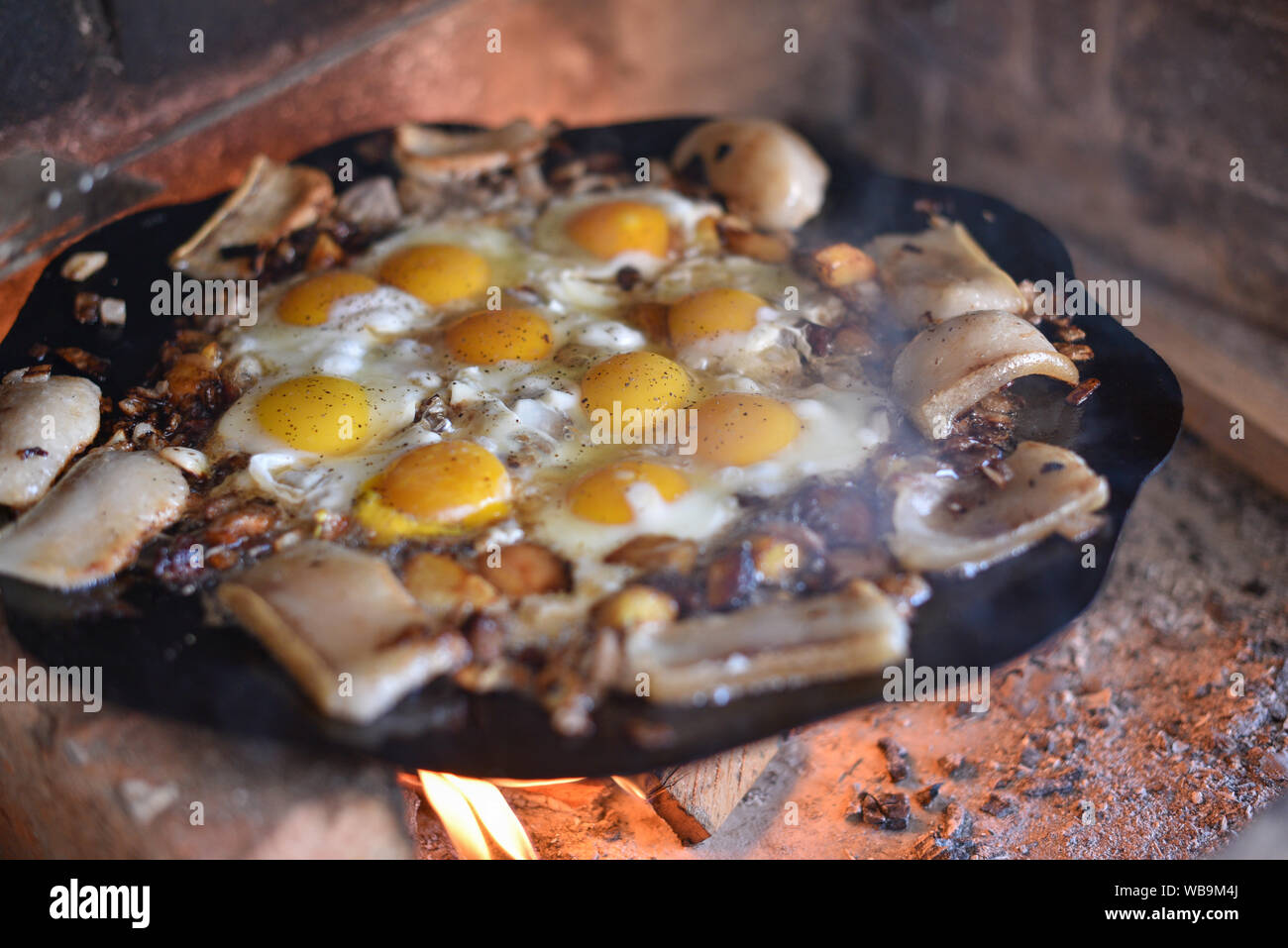 Eier sind bei einem Brand in der Straße Fried. Spiegeleier mit Speck. Ein Teller viele Spiegeleier auf ein Feuer im Ofen. Korn Fett. Street Food. Rest mit f Stockfoto