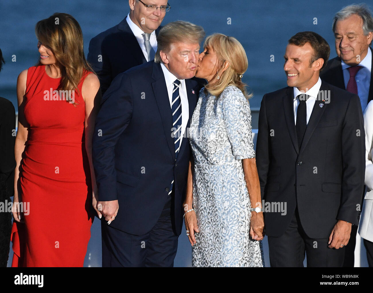 Der französische Präsident Emmanuel Längestrich beobachtet, wie seine Frau Brigitte Längestrich küsse Präsident Donald Trump, wie er mit der ersten Dame Melania Trump steht, wie Sie andere Führer der Welt für die Familie Foto auf dem G7-Gipfel in Biarritz, Frankreich. Stockfoto