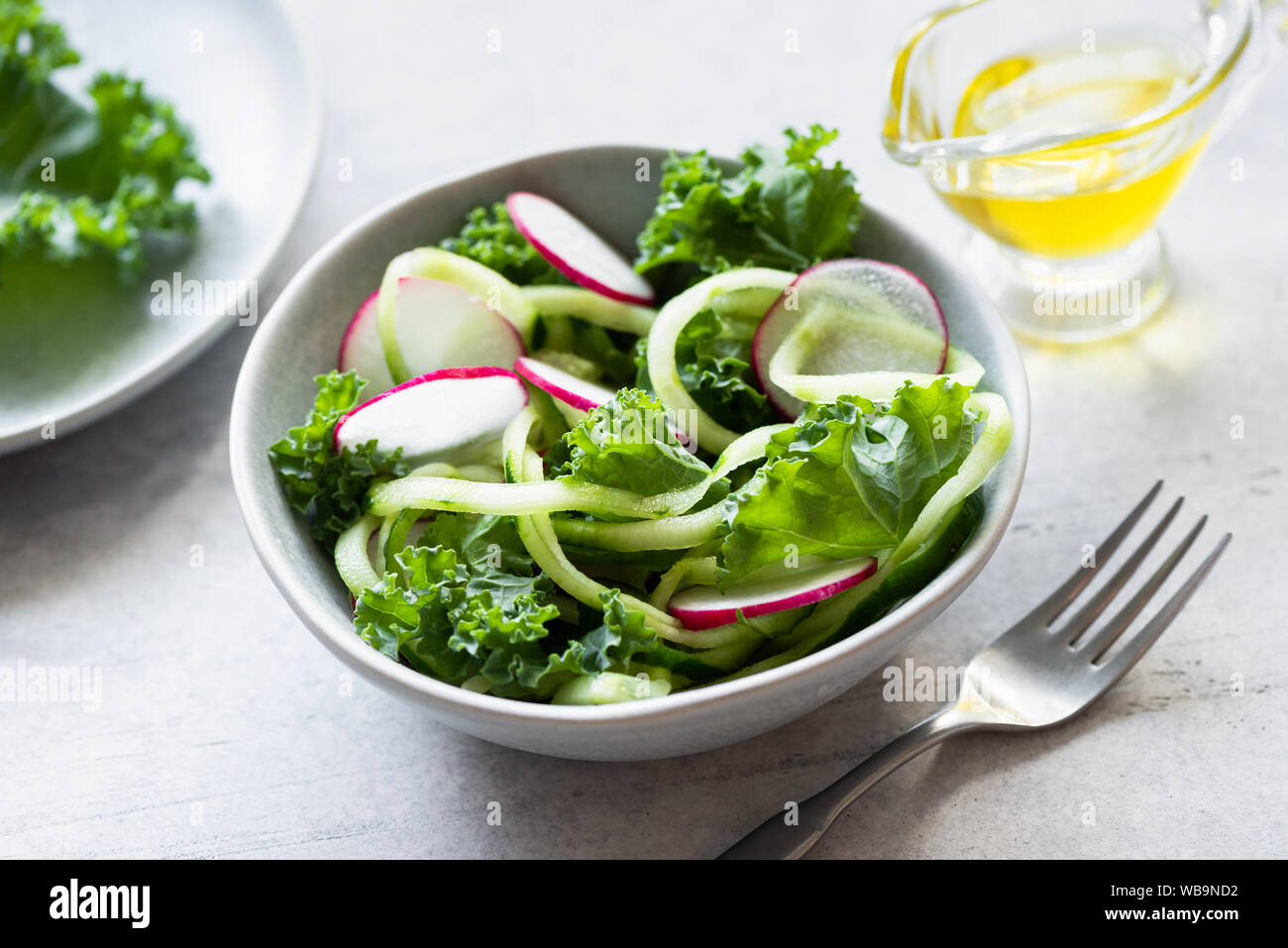 Vegan grüner Salat mit Kohl, Gurken und Radieschen gekleidet mit natives Olivenöl extra Stockfoto