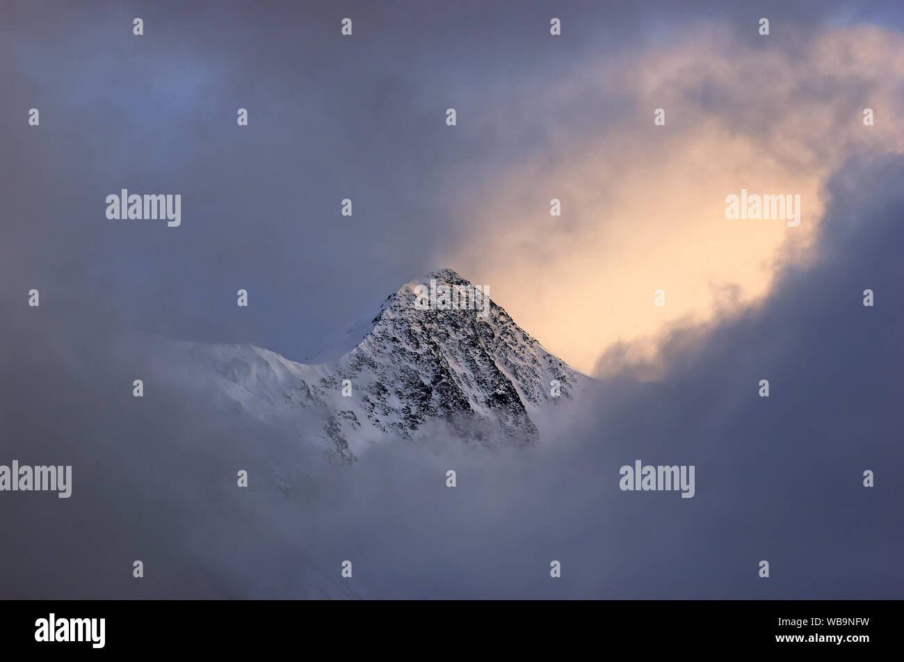 Belukha Mountain Top durch die Wolken bei Sonnenuntergang umgeben. Altai, Russland Stockfoto
