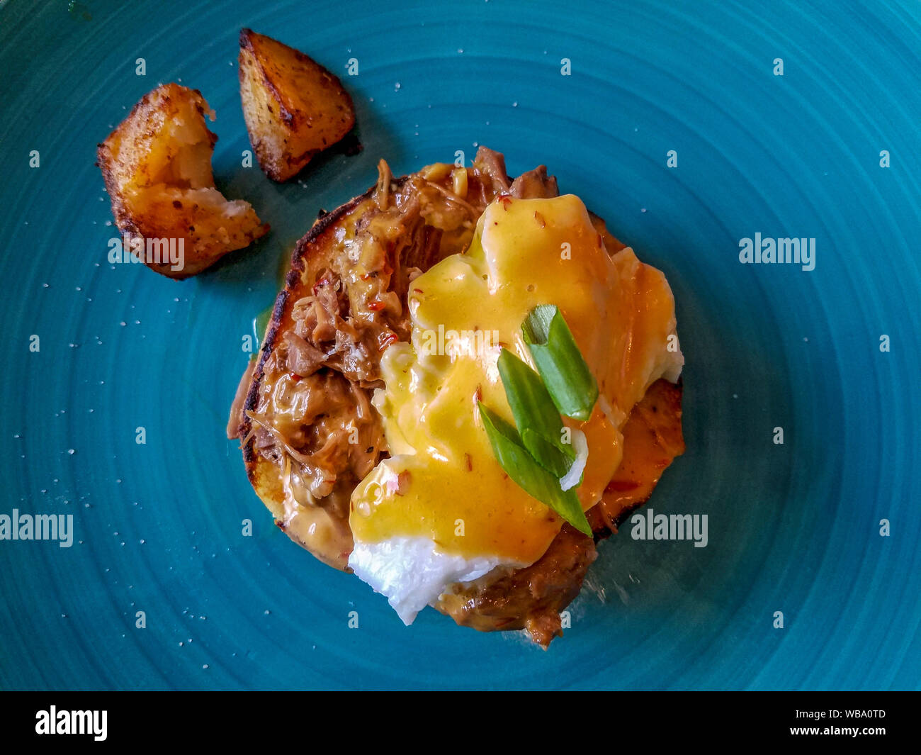 Schweinefleisch adobo Benedikt, schweineschulter geschmort in Soja und Essig auf Englische Muffins im Cosmos Bistro, eine Innenstadt Cafe serviert Speisen mit Flair gewartet. Stockfoto