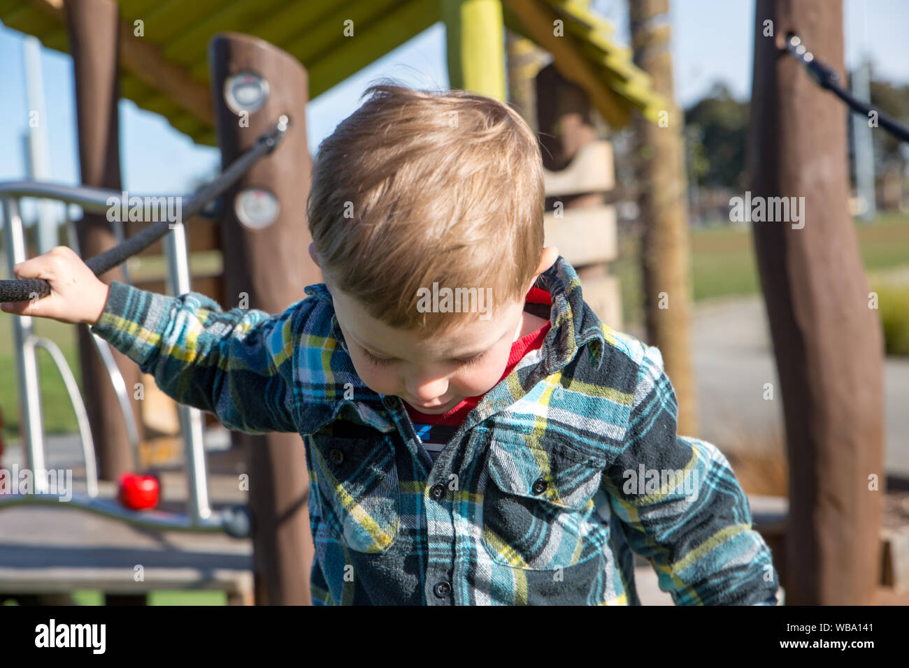 Ein kleiner Junge sorgfältig Praktiken, die über die Hängebrücke auf dem Spielplatz fort Stockfoto