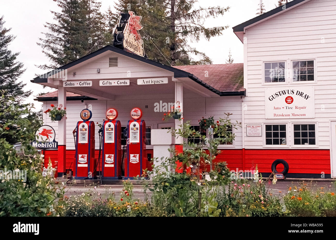 Der am meisten fotografierte Gas Station in Alaska, USA, ist diese bemerkenswerte Nachbildung eines Vintage vor dem Zweiten Weltkrieg Mobil Tankstelle mit drei klassischen Amerikanischen Zapfsäulen dating bis 1937, Benzin und Dieselkraftstoff und Herd Öl in der kleinen Stadt Gustavus verzichten. Die bunten Tankstelle wird von der Gustavus Dray store, Häuser in Alaska nur Petroleum Museum betrieben und verkauft auch Souvenirs, Antiquitäten, Bücher, Snacks und Getränke. Dies ist die einzige Tankstelle in Gustavus, die nur auf dem Luft- oder Seeweg erreicht werden kann und nur 20 Meilen (32 Kilometer) von asphaltierten Straßen. Stockfoto